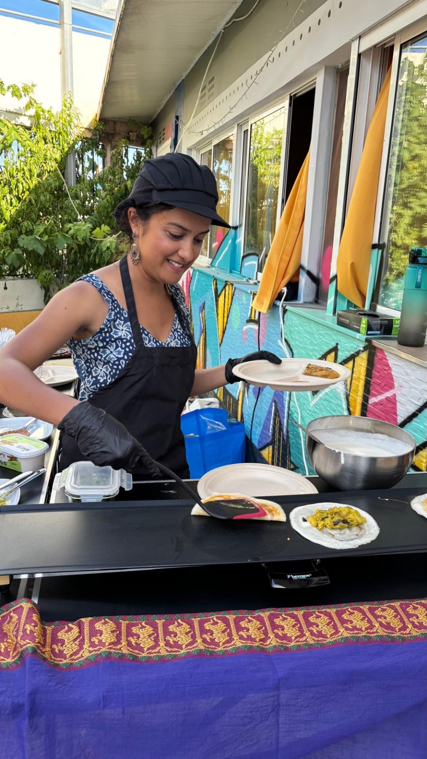 Anitha folding a dosa at an outdoor catering station