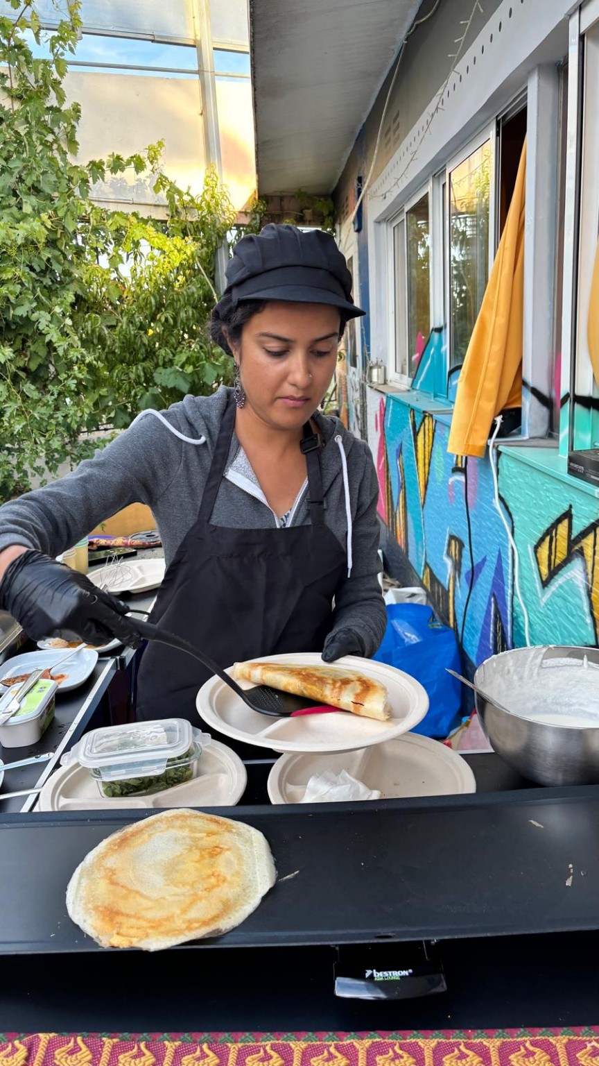 Anitha placing a freshly folded dosa onto a guest’s plate