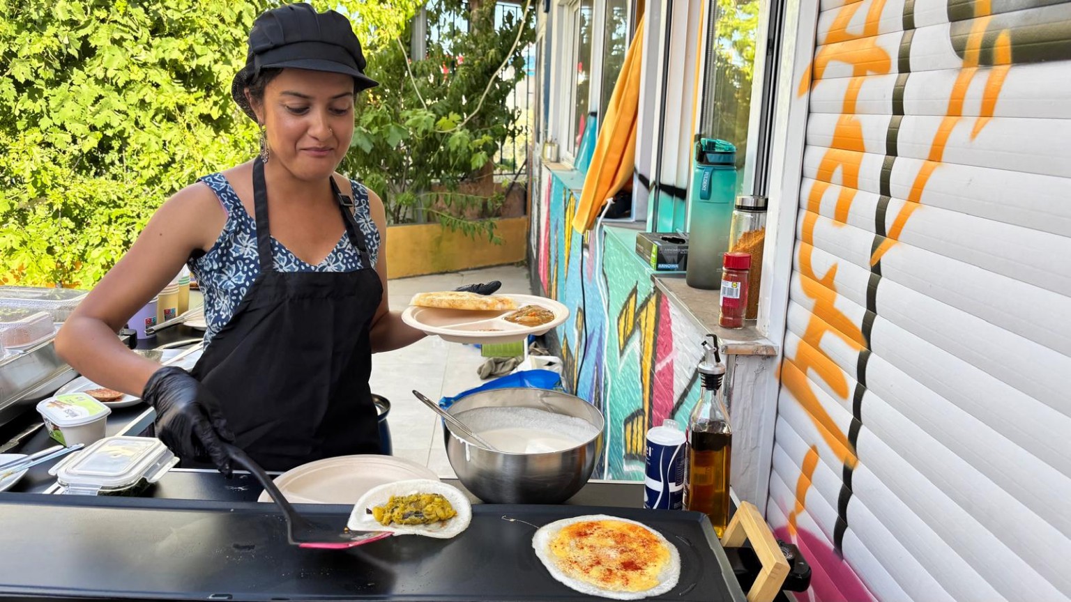 Anitha lifting a potato masala dosa from the outdoor griddle